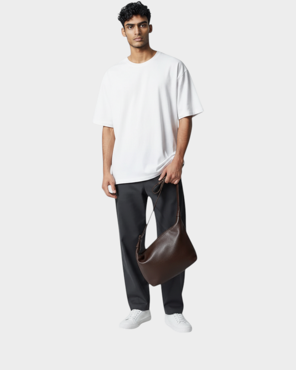 SIEVRA Drift slouchy brown cowhide and leather shoulder bag held by a man in a white t-shirt and dark trousers