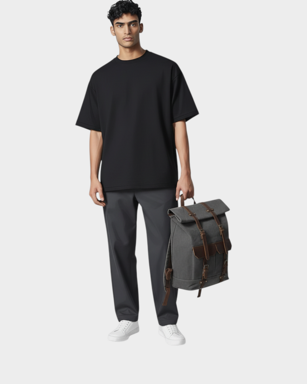 SIEVRA Trail Backpack in army green oil wax canvas with brown leather straps held by a man in a black t-shirt
