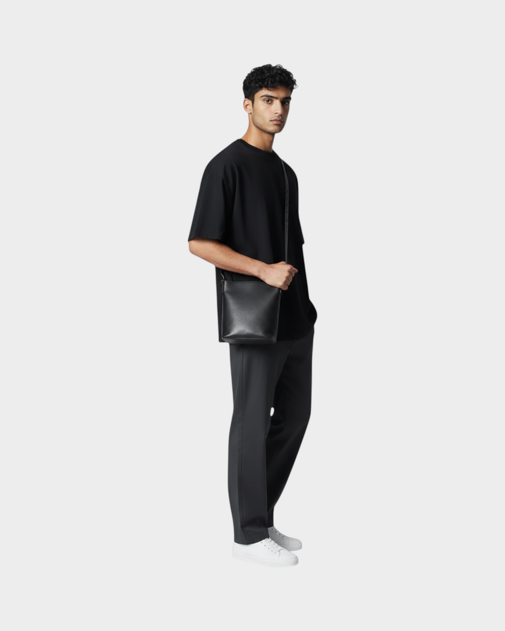 SIEVRA Basin black full-grain cowhide leather bucket crossbody bag worn by a man in a black t-shirt and trousers.