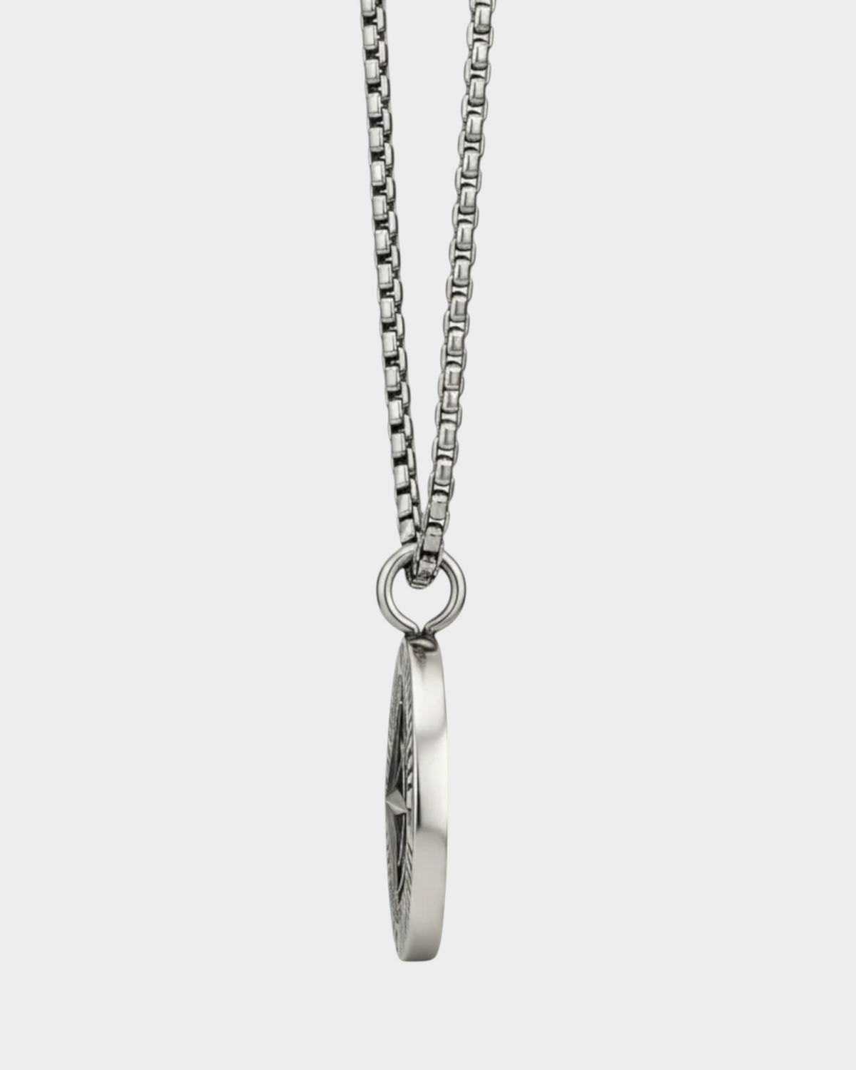 SIEVRA Bearing pendant necklace featuring a stainless steel compass medallion on a curb chain, side view.